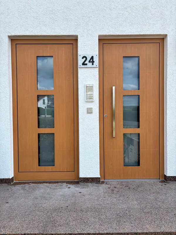 Zwei Haustüren in Holzoptik mit Glaseinsätzen an einem Doppelhaus
