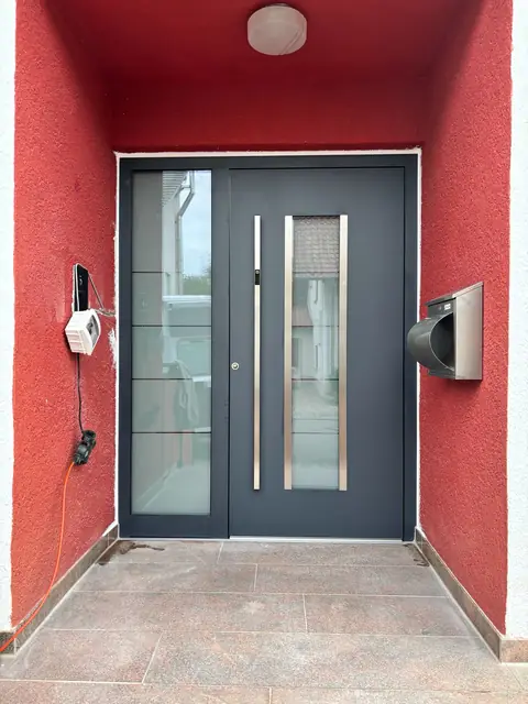 Nachher: anthrazitfarbene Haustür mit Glas-Seitenteil in roter Eingangsnische